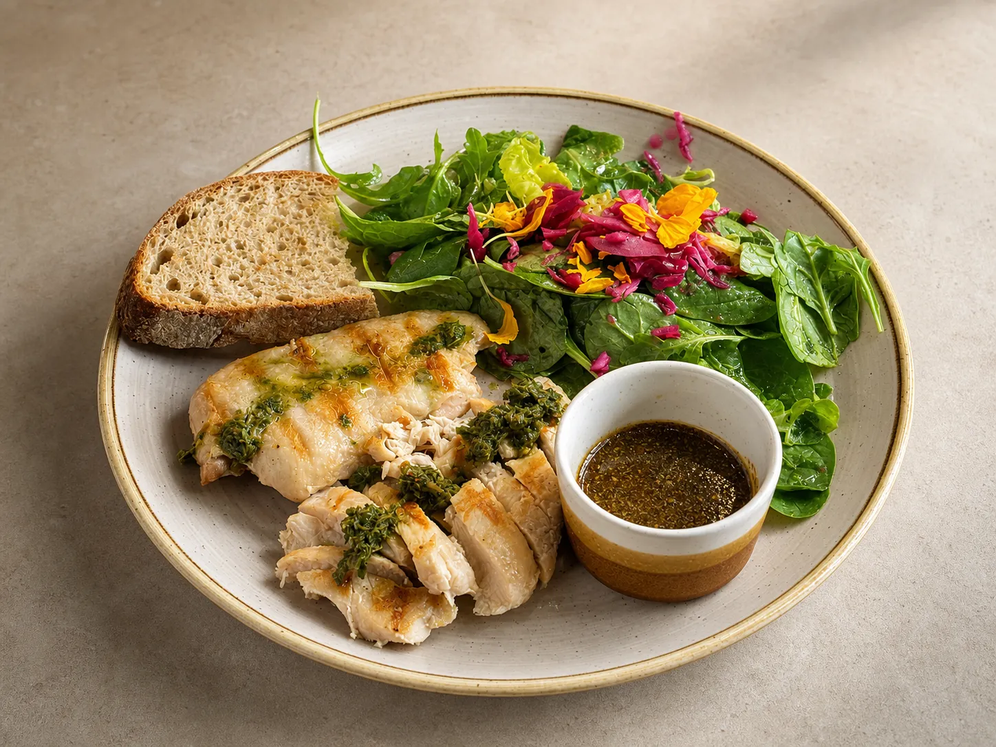 Grilled chicken breast with chimichurri, a slice of sourdough and a dressed green salad on an era. plate